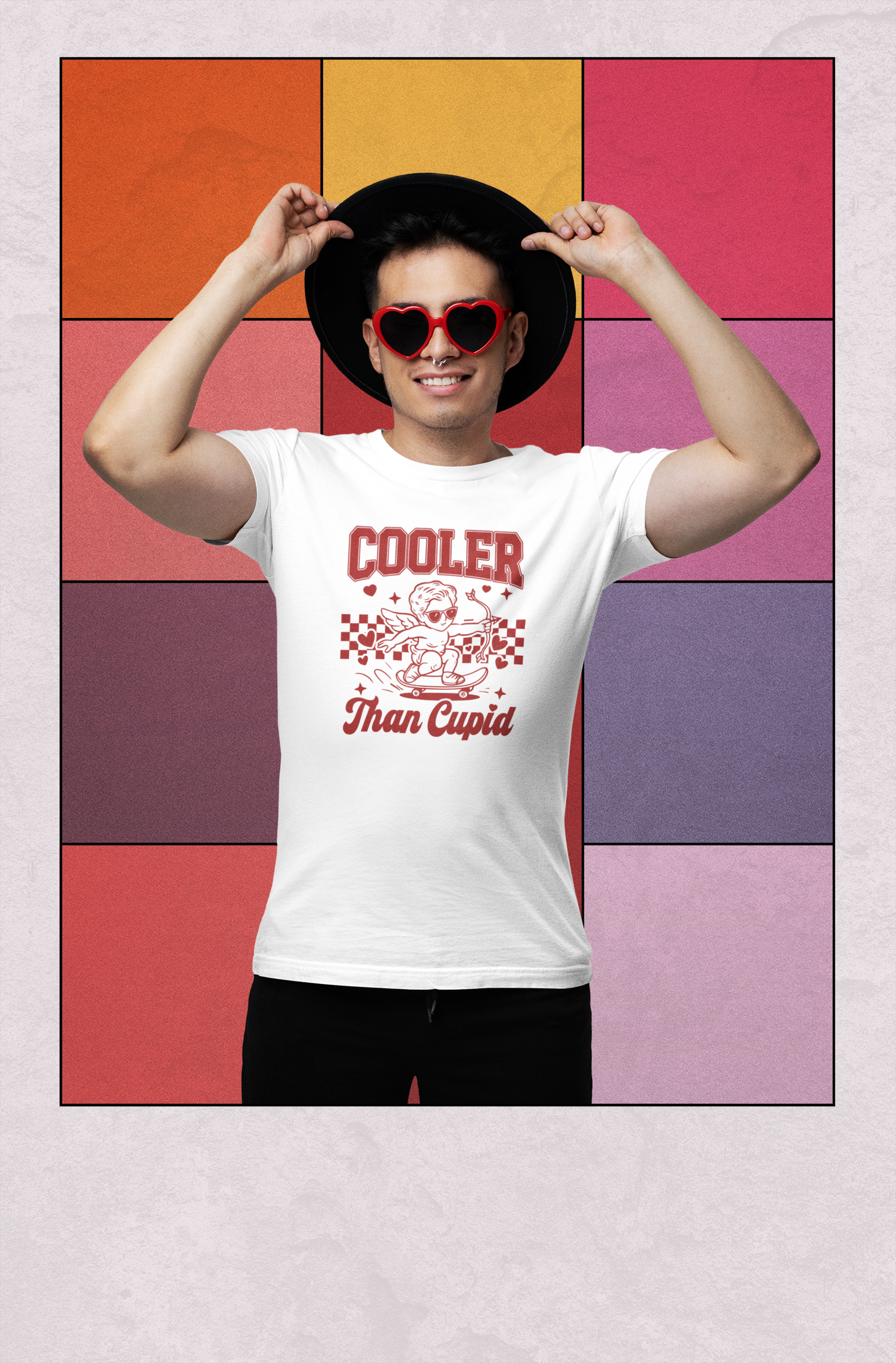 Person wearing a white t-shirt with a graphic design and text, standing against a colorful geometric-patterned background. Cooler Than Cupid T‑Shirt — Retro Skater Valentine Tee