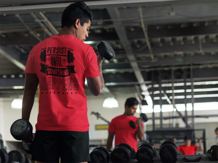 Person lifting weights in a gym wearing a red t-shirt with motivational text. Persist Until Something Happens Gym T-Shirt — Motivational Workout Tee