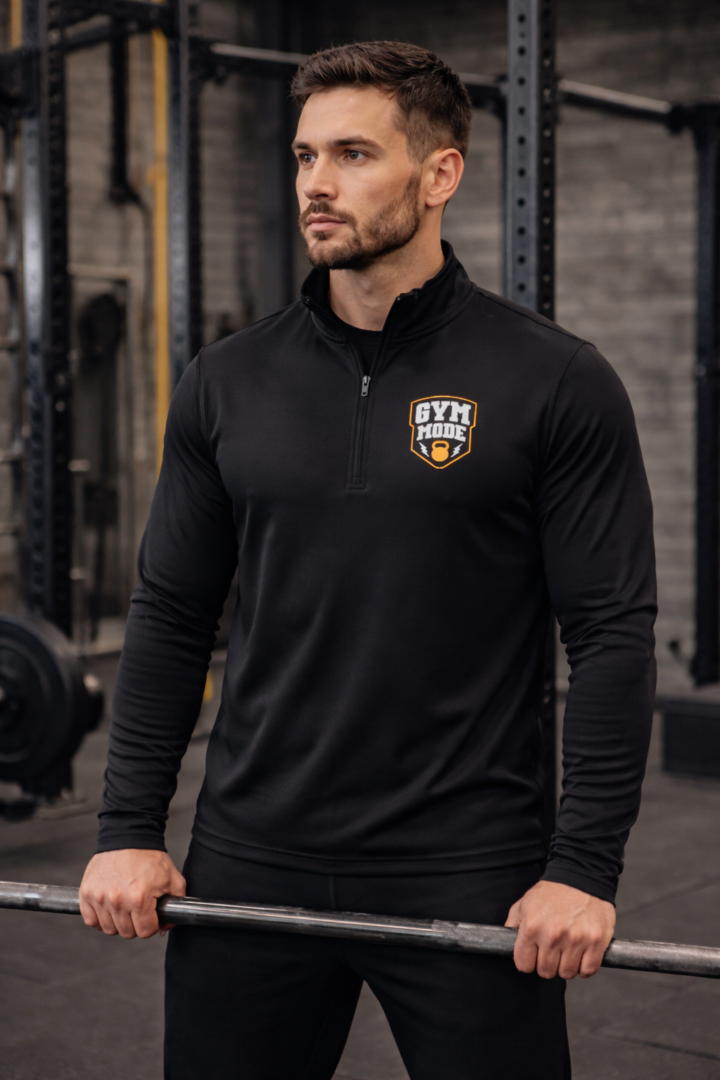 Man wearing a black Quarter-Zip Pullover with a 'Gym Mode'  Rustic Shield Logo, holding a barbell in a gym setting.